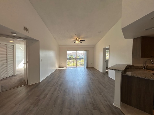 unfurnished living room featuring ceiling fan, high vaulted ceiling, sink, and dark hardwood / wood-style flooring