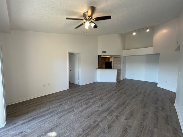 unfurnished living room featuring high vaulted ceiling, dark wood-type flooring, a textured ceiling, and ceiling fan