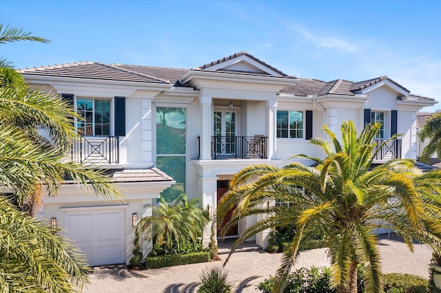 view of front of property featuring decorative driveway, a tile roof, stucco siding, and a balcony