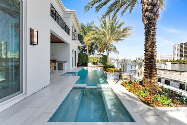 view of swimming pool with a water view, a pool with connected hot tub, and a patio area