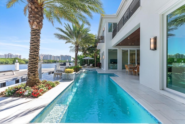 pool featuring outdoor dining space, a patio area, and a city view