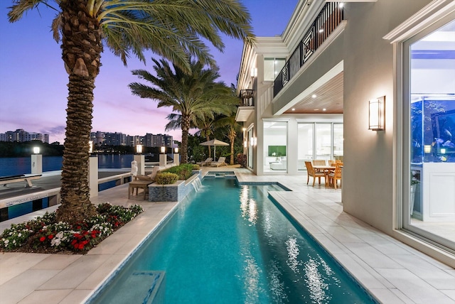 pool with a patio area, outdoor dining space, and a water view