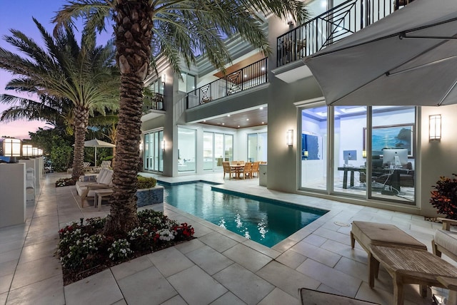 pool at dusk featuring an outdoor pool and a patio