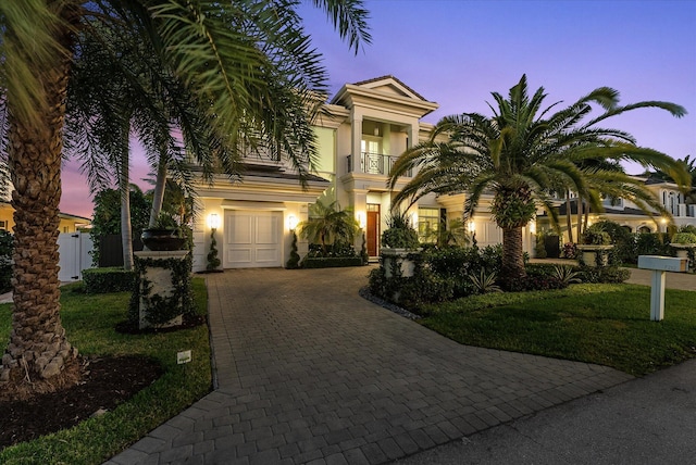 mediterranean / spanish-style home featuring decorative driveway, a front lawn, stucco siding, a garage, and a balcony