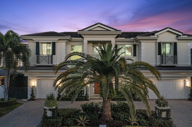 view of front of home with decorative driveway, an attached garage, and stucco siding