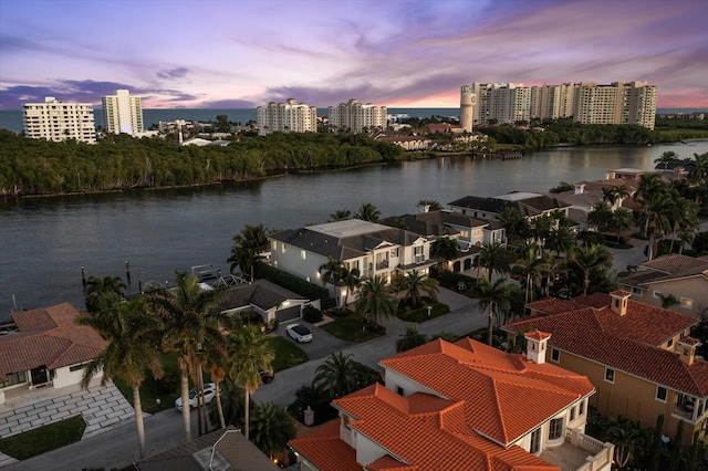 aerial view at dusk featuring a water view and a view of city