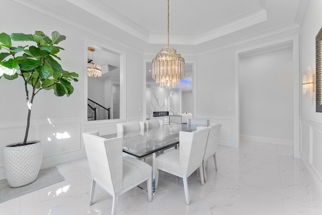 dining room with a decorative wall, a notable chandelier, marble finish floor, and a tray ceiling