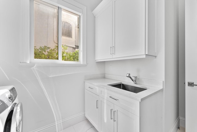 laundry room with baseboards, cabinet space, washer and dryer, and a sink