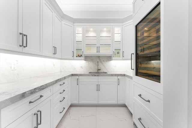 kitchen featuring beverage cooler, light stone countertops, marble finish floor, and white cabinetry