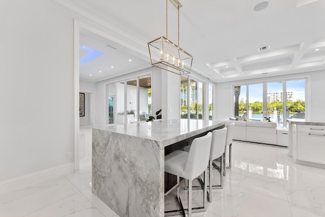 kitchen with light stone countertops, marble finish floor, white cabinets, hanging light fixtures, and open floor plan