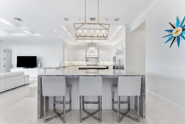 kitchen with pendant lighting, light stone counters, a kitchen breakfast bar, white cabinetry, and open floor plan