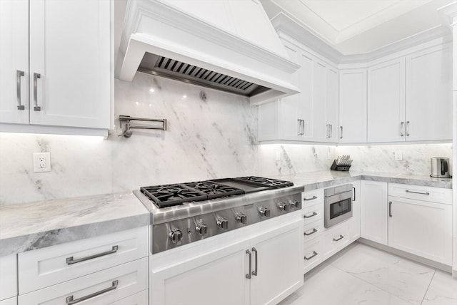 kitchen with custom range hood, appliances with stainless steel finishes, marble finish floor, white cabinetry, and light stone countertops