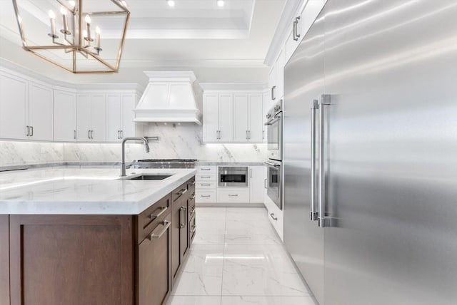 kitchen with light stone countertops, built in appliances, marble finish floor, white cabinets, and a sink