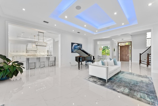 living area featuring ornamental molding, a raised ceiling, marble finish floor, and stairs