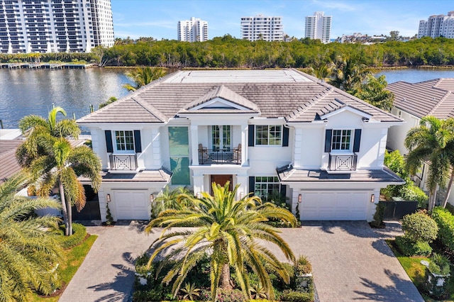 view of front of property with a water view, an attached garage, a balcony, and stucco siding