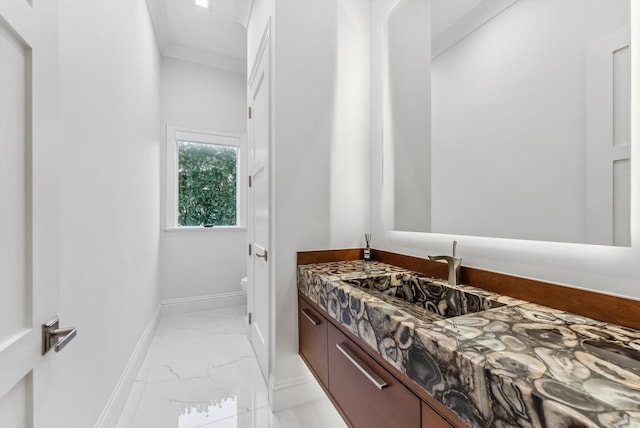 half bathroom featuring toilet, marble finish floor, ornamental molding, baseboards, and vanity