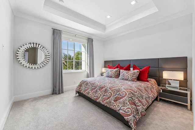 bedroom with baseboards, light colored carpet, and a tray ceiling