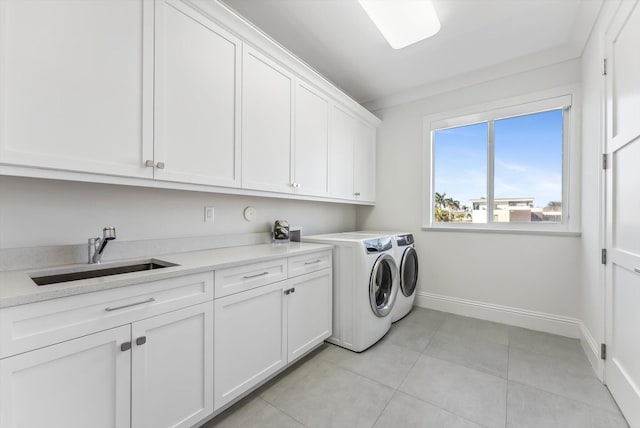 laundry area with separate washer and dryer, cabinet space, baseboards, light tile patterned floors, and a sink