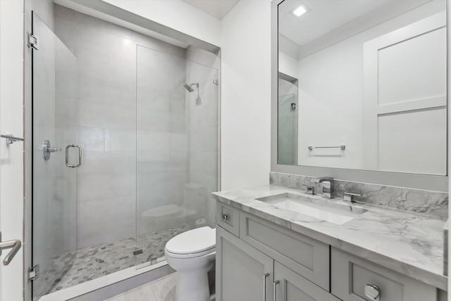 bathroom with toilet, a stall shower, and vanity