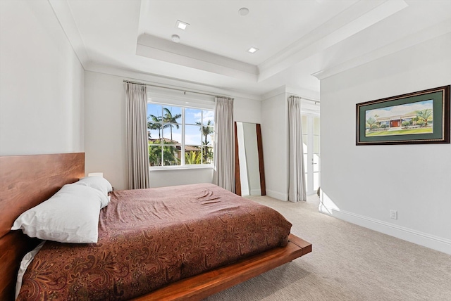 bedroom with crown molding, light carpet, baseboards, and a tray ceiling