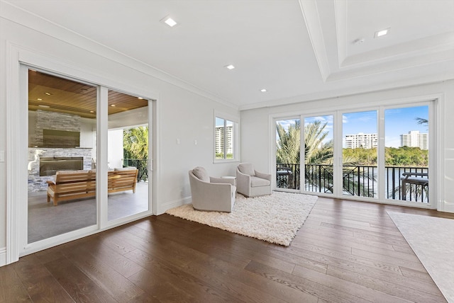 unfurnished room featuring a fireplace, a water view, crown molding, baseboards, and dark wood finished floors