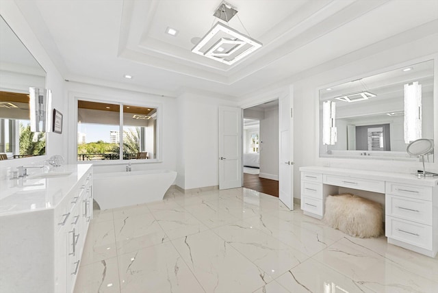 bathroom with a raised ceiling, a soaking tub, vanity, and marble finish floor