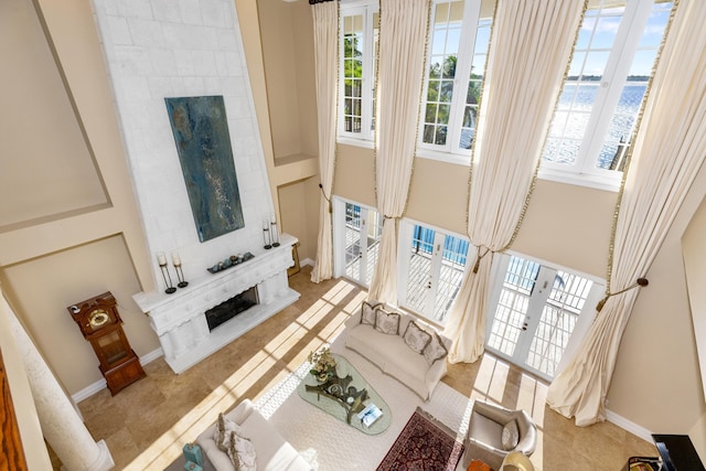 tiled living area with a water view, a fireplace, and baseboards