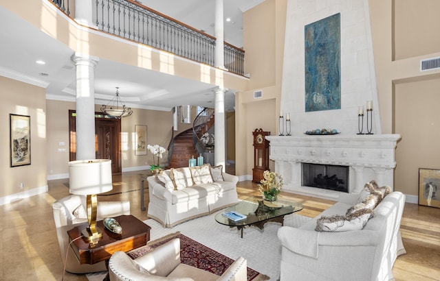 living area with crown molding, decorative columns, visible vents, a tile fireplace, and baseboards