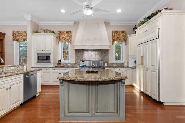 kitchen with premium range hood, a kitchen island, a sink, appliances with stainless steel finishes, and backsplash