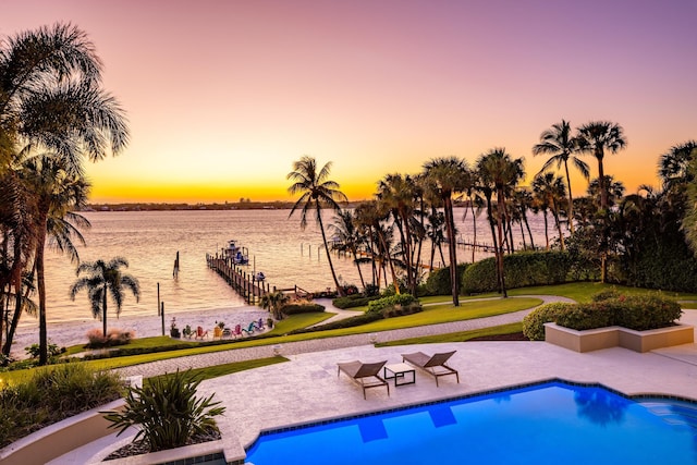 pool at dusk featuring a water view