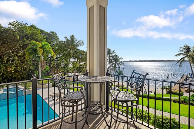 balcony with a water view and a pool with connected hot tub