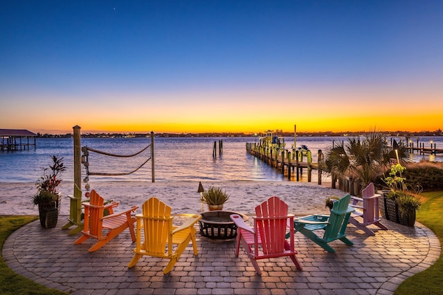 view of patio / terrace featuring an outdoor fire pit, a water view, and a dock