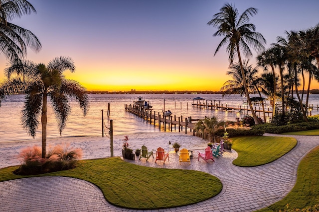 view of community with a dock, a water view, and a lawn