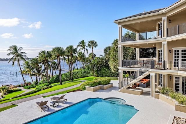 outdoor pool with french doors, a yard, a patio, a water view, and stairs