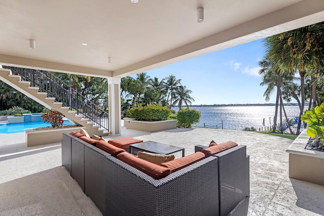 view of patio / terrace with a water view, stairway, an outdoor pool, and an outdoor living space