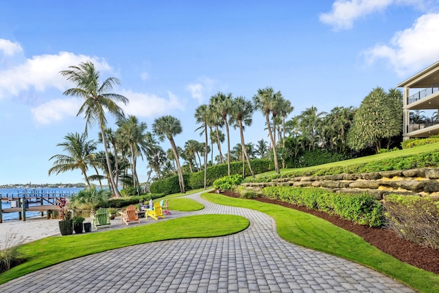 view of property's community with a water view, a patio area, and a yard