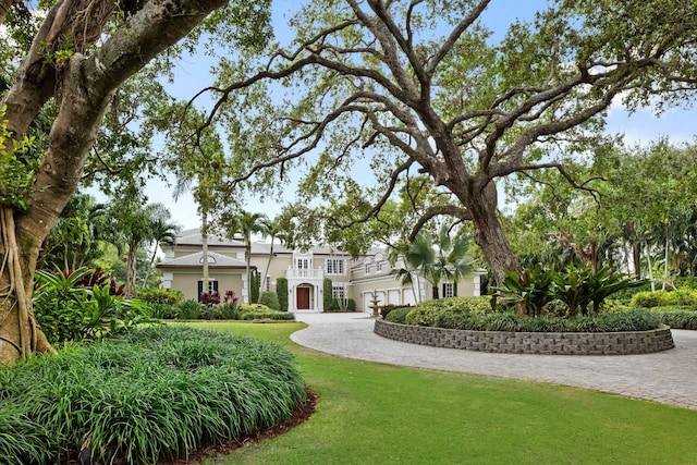 view of front facade featuring driveway, a front lawn, and a balcony