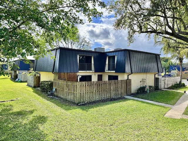 view of front of home with a front yard, metal roof, fence, and mansard roof