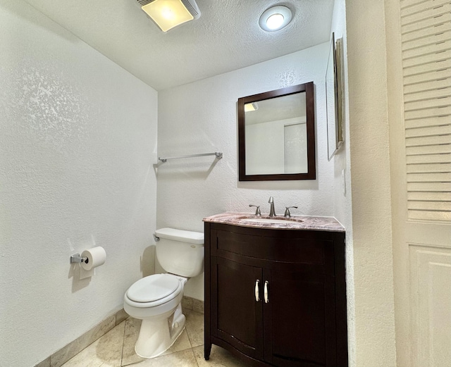 bathroom with a textured ceiling, a textured wall, tile patterned flooring, toilet, and vanity