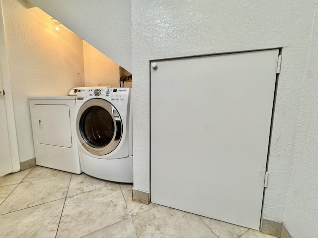 laundry room with laundry area, washer and clothes dryer, and a textured wall