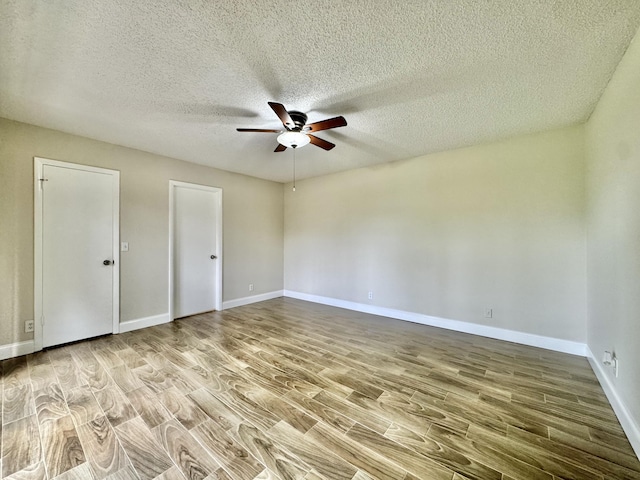 unfurnished room featuring ceiling fan, a textured ceiling, baseboards, and wood finished floors