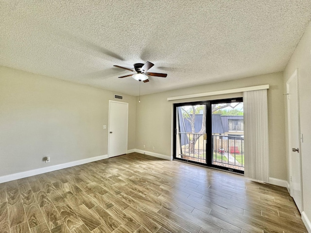 spare room with baseboards, visible vents, ceiling fan, wood finished floors, and a textured ceiling