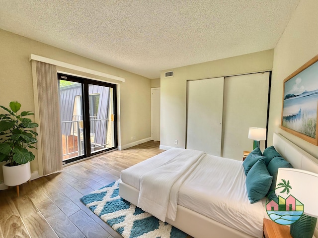 bedroom featuring visible vents, wood finished floors, access to outside, a textured ceiling, and a closet