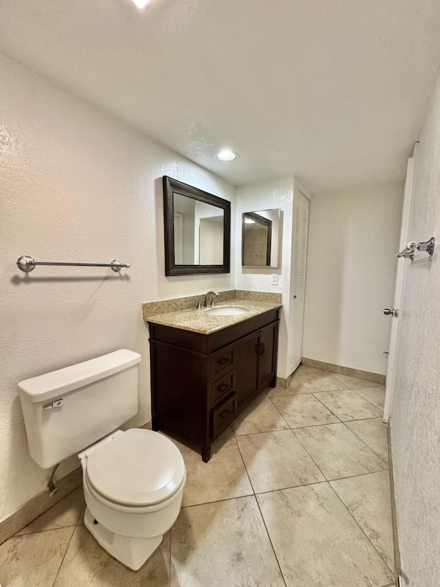 bathroom with baseboards, vanity, and toilet