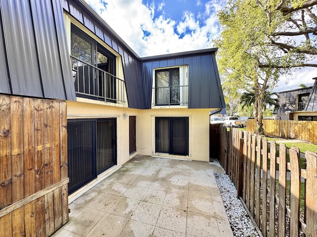 exterior space with a balcony, fence, a patio, and stucco siding