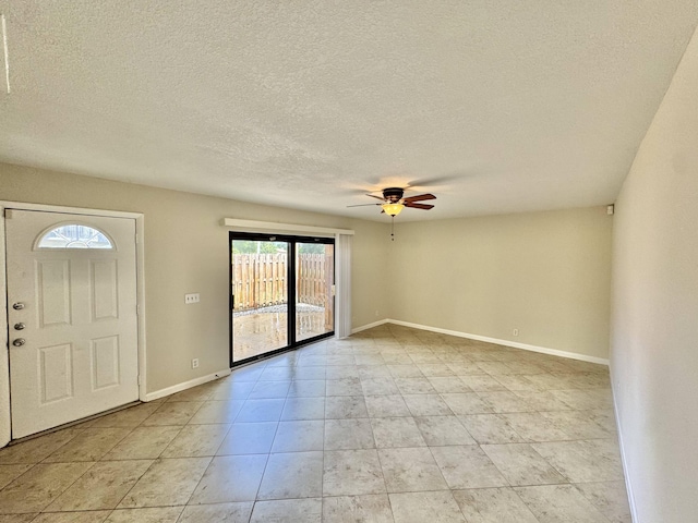 foyer with light tile patterned floors, ceiling fan, baseboards, and a textured ceiling