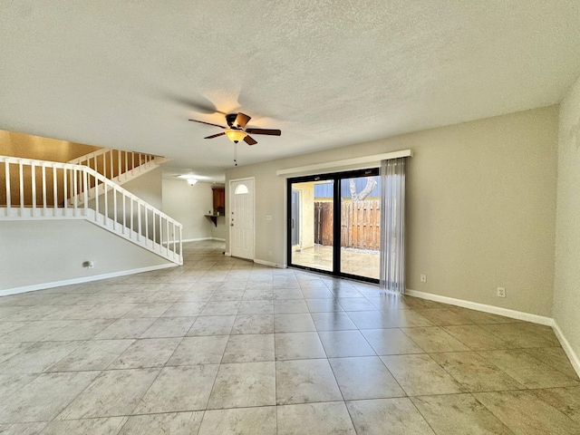 unfurnished room featuring light tile patterned floors, baseboards, ceiling fan, stairway, and a textured ceiling