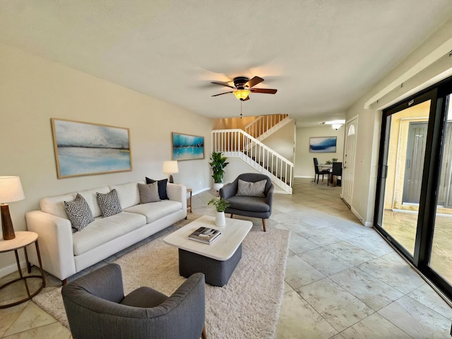 living area with ceiling fan, stairs, and baseboards