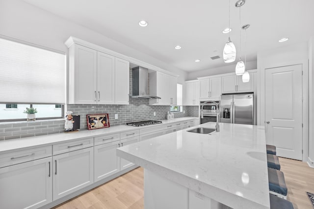 kitchen with wall chimney exhaust hood, stainless steel appliances, sink, and white cabinets