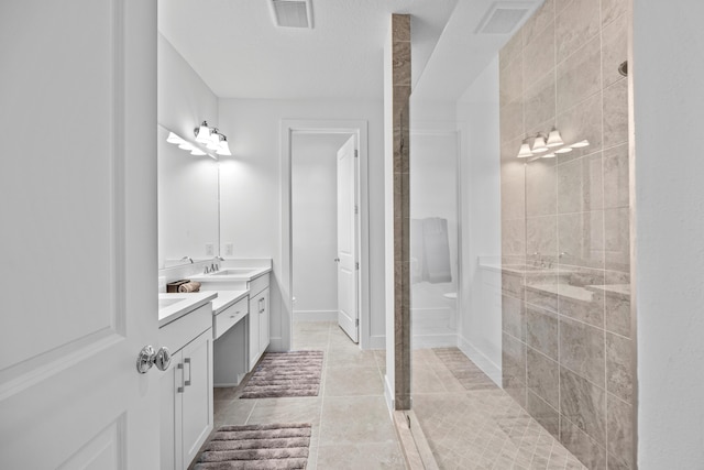 bathroom featuring tiled shower, vanity, and tile patterned flooring